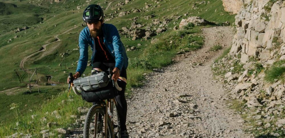 11un uomo si muove in bici su un sentiero per dimostrare Come viaggiare in modo sostenibile