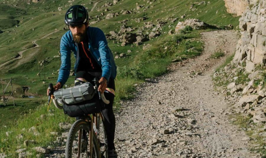 11un uomo si muove in bici su un sentiero per dimostrare Come viaggiare in modo sostenibile